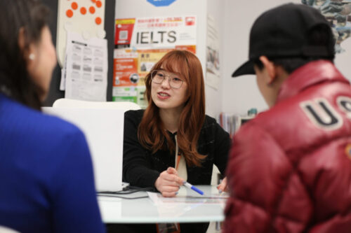 UKPLUS Osaka 英語学習カウンセリング UKPLUS Osakaの受付でスタッフがお客様に英語コースについてアドバイスしている様子