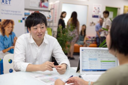 UKPLUS Osakaの受付でIELTS受講生がスタッフから学習について個別相談を受けている様子